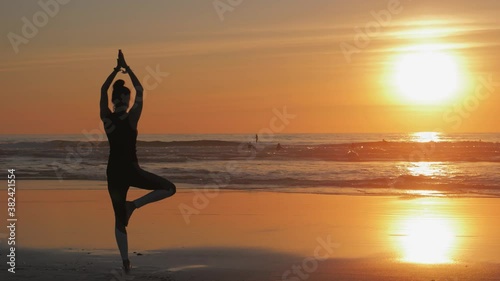 Silhouette of slim woman with arms raised up, Practice of yoga on the beach