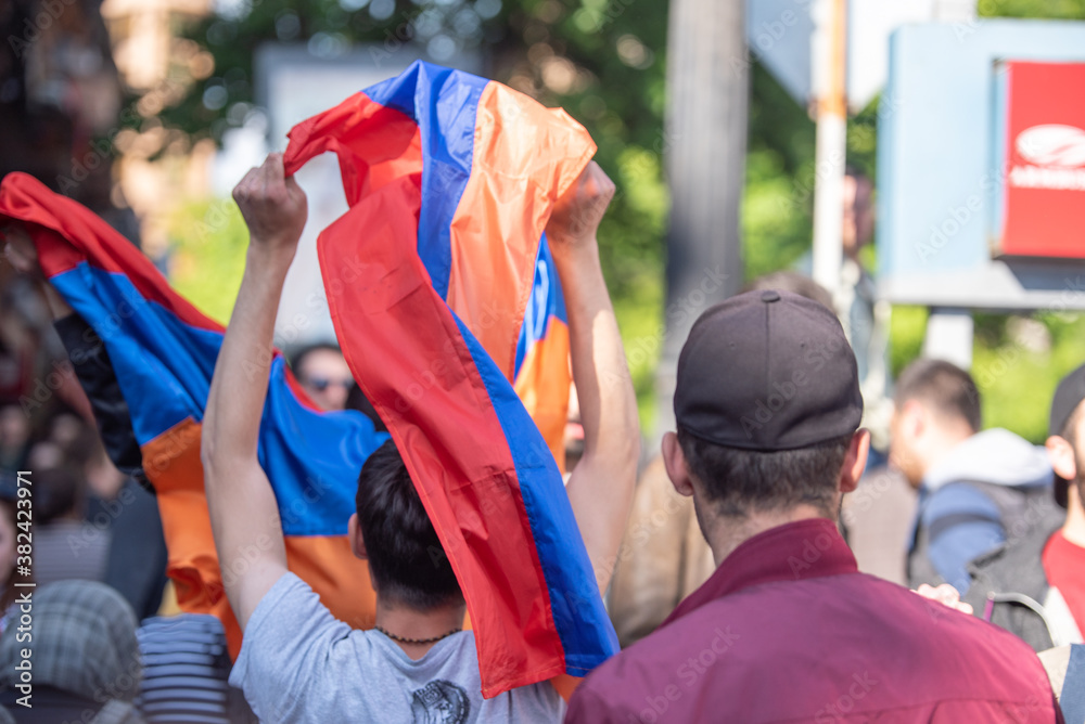 Yerevan, Armenia - April, 23, 2018: People celebrate Victory in Velvet Revolution in Yerevan, Armenia. Men raising Armenian flags. Back View. April, 23, 2018. Peaceful protests. Yerevan, Armenia - April, 23, 2018: People celebrate Victory in Velvet Revolution in Yerevan, Armenia. Men raising Armenian flags. Back View. April, 23, 2018. Peaceful protests.