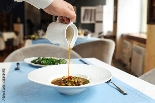 Pouring broth in a plate with spanish oxtail soup photo