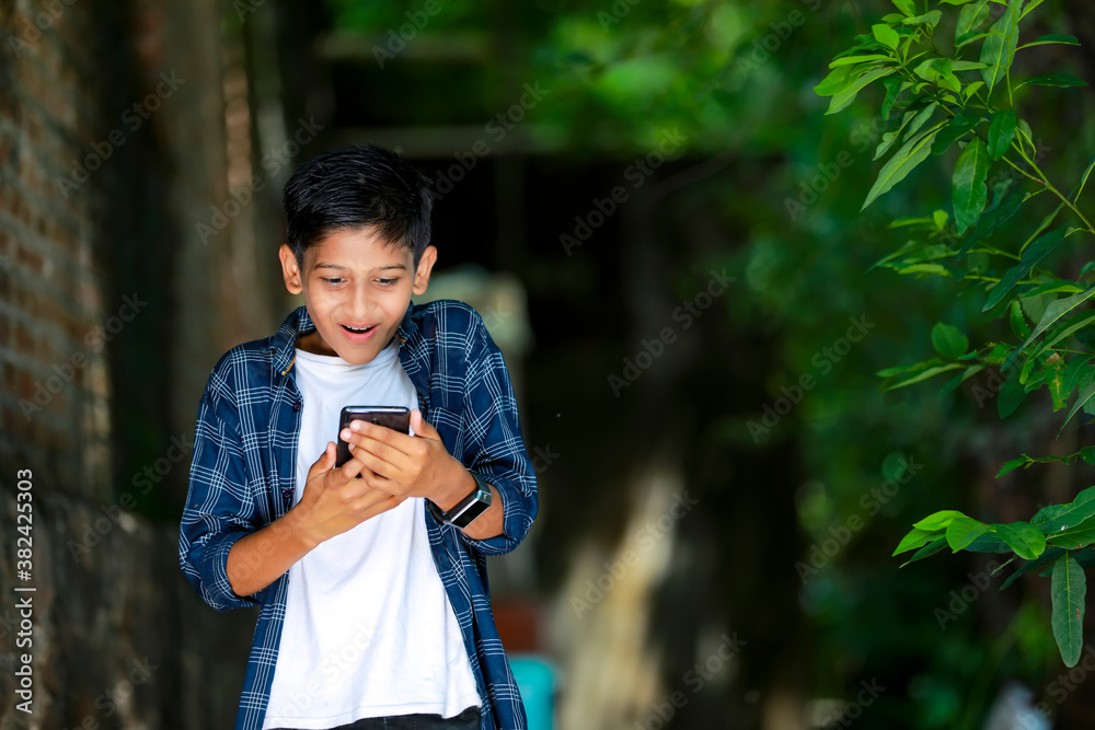 childhood, technology and people concept - indian cute school boy showing smartphone with blank screen childhood, technology and people concept - indian cute school boy showing smartphone with blank screen