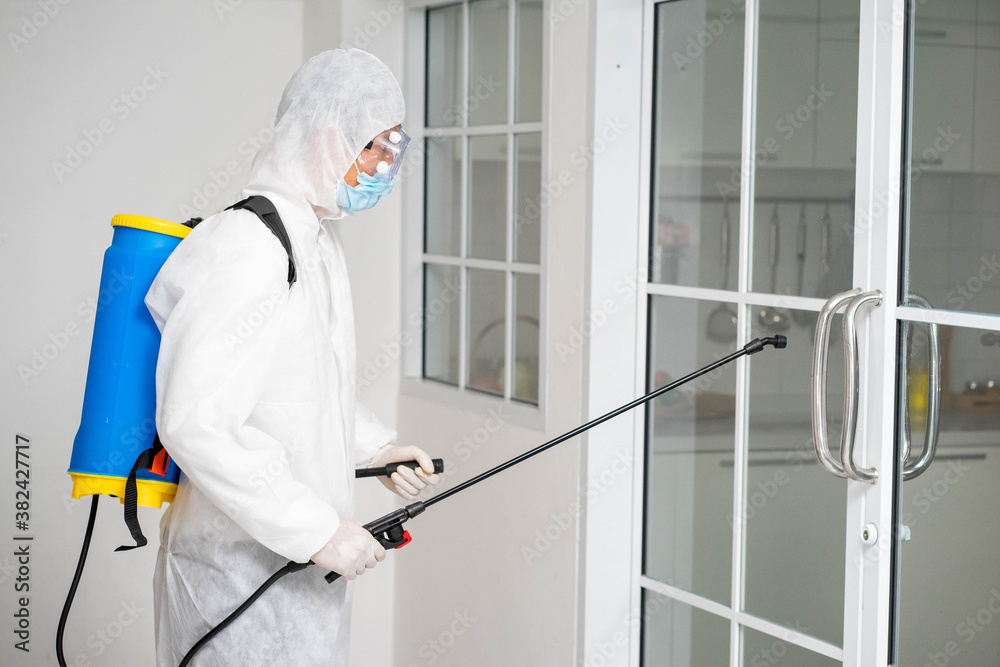 health care worker in white jumpsuit and protective face mask using spraying machine to disinfect virus pandemic.  Health care and midicine concept. New normal social distancing concept.