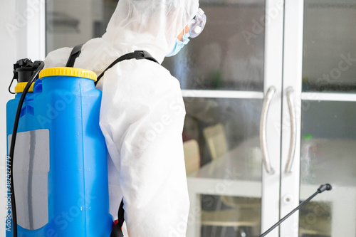 health care worker in white jumpsuit and protective face mask using spraying machine to disinfect virus pandemic.  Health care and midicine concept. New normal social distancing concept. photo