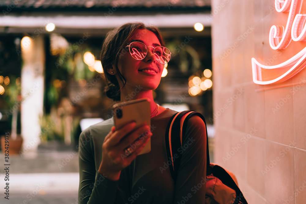 Trendy woman with smartphone on street in neon light - obrazy, fototapety, plakaty 
