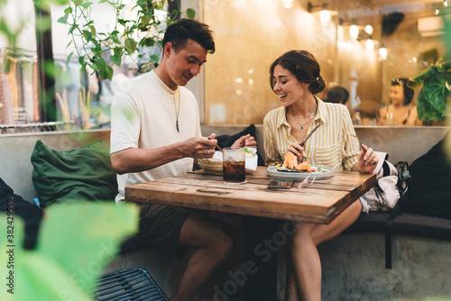 Happy multiethnic couple eating in modern cafe