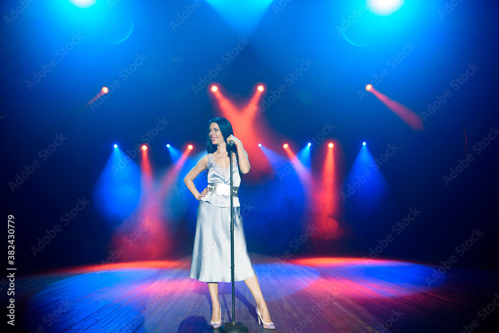 Bright stage lighting. Vocalist singing to microphone.
