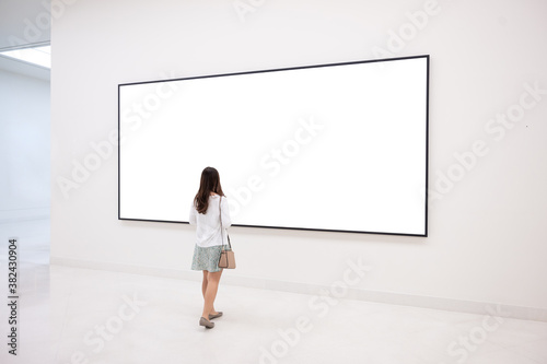 young woman standing in a room looking at the empty mockup frames billboard