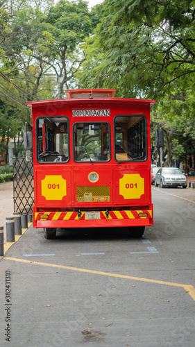Front Side of a Red and Yellow Tram Under the Trees from Coyoacan
