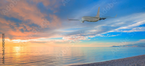 Airplane taking off from the airport - Passenger airplane flying above tropical sea at amazing sunset