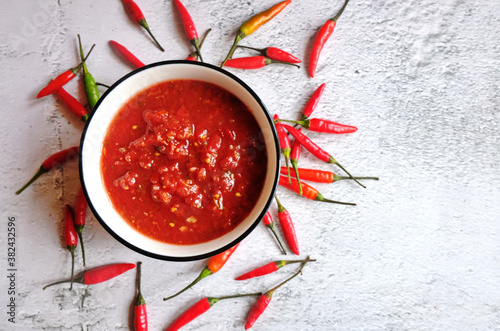 Small bowl of homemade harissa with red chili. Adjika, hot harissa sauce - spicy hot paste of chilli pepper on white background. Copy spase