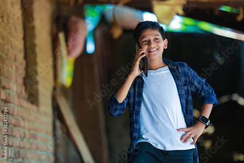 people, children, technology and communication concept - cute indian child talking on smartphone