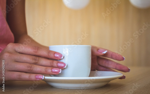 The girl's hands on the mug. Beautiful manicure and morning coffee