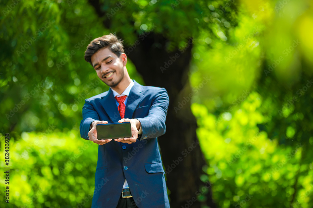 Happy businessman pointing finger on blank smartphone screen Happy businessman pointing finger on blank smartphone screen
