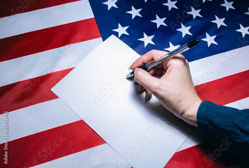 Elections in the USA. Woman putting tick on the paper for vote. Political changes in the country. Copy space place. American flag. 