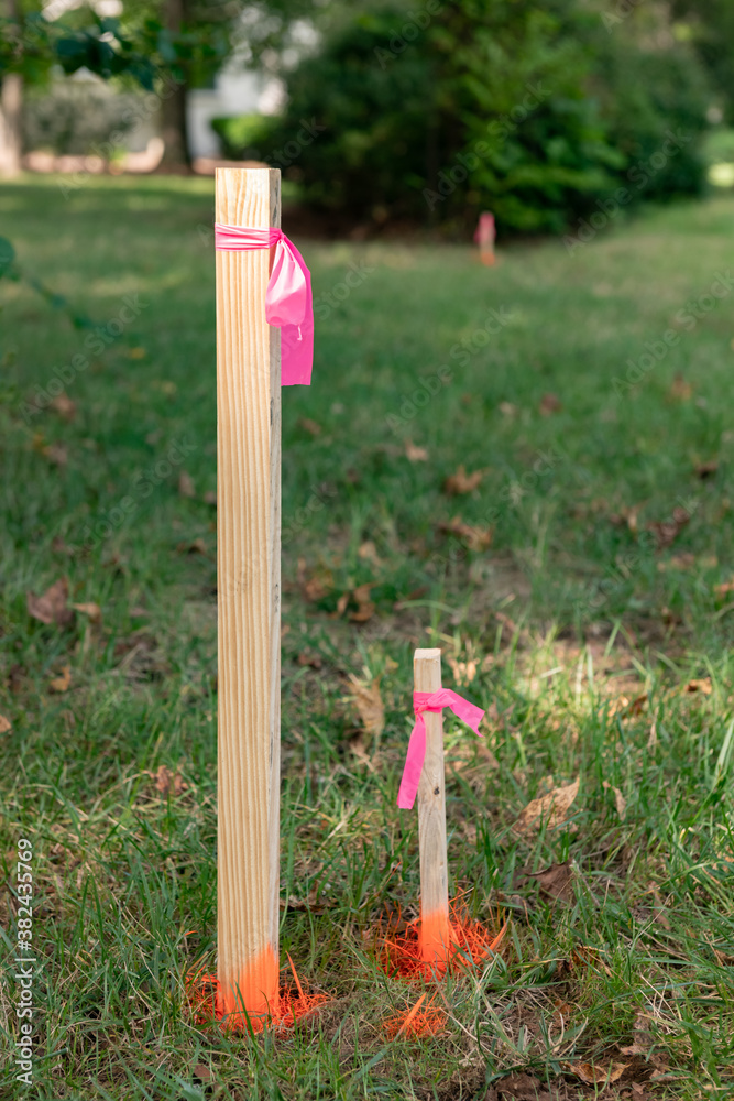 Survey stakes with orange pink ribbons indicating property lines with a  shallow depth of field and copy space Stock Photo