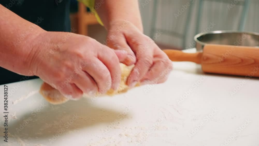 Close up of grandmother hands kneading on table in home kitchen. Retired elderly baker with bonete mixing ingredients with sifted wheat flour kneading for baking traditional cake and bread. Close up of grandmother hands kneading on table in home kitchen. Retired elderly baker with bonete mixing ingredients with sifted wheat flour kneading for baking traditional cake and bread.