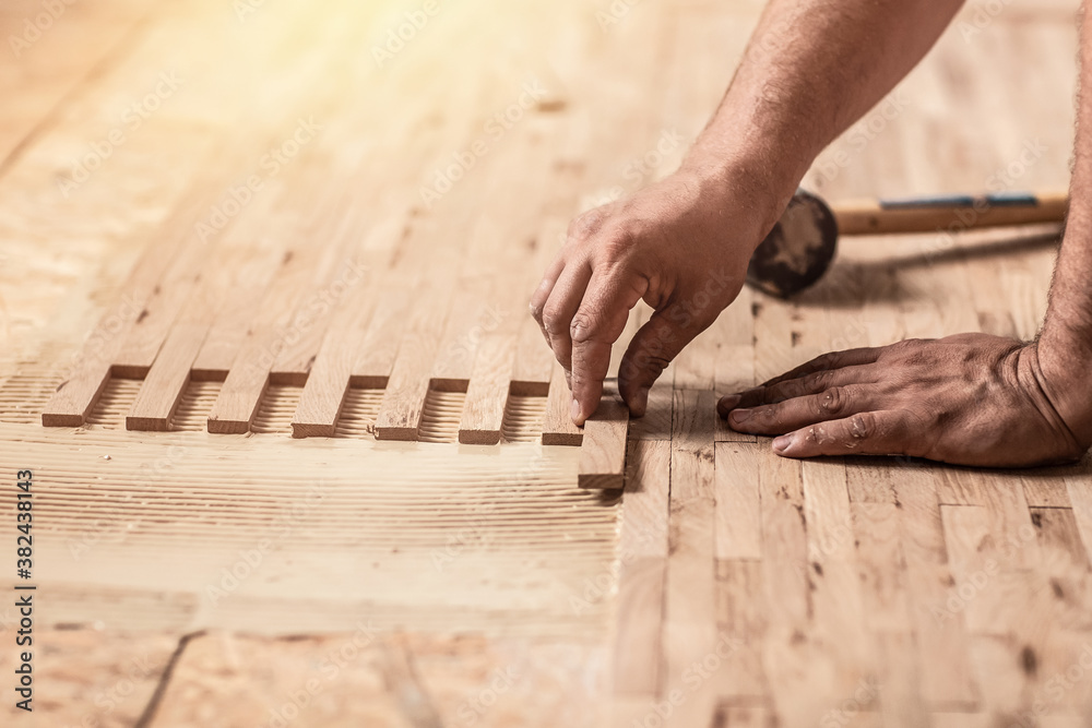 Worker installing wood parquet. Carpenter on work laying laminate or parquet flooring. installation of parquet. Home renovation, Close up Worker installing wood parquet. Carpenter on work laying laminate or parquet flooring. installation of parquet. Home renovation, Close up