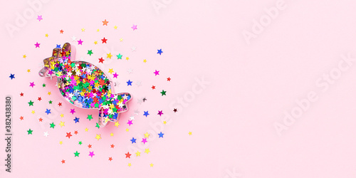 Festive banner with creative composition made of cookie form and colorful confetti at pastel pink background. Minimal concept.