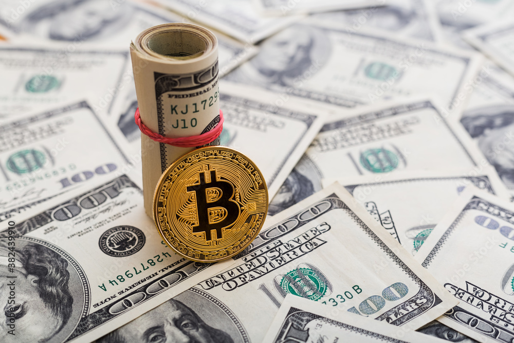 Fototapeta premium Golden Bitcoin coin on a us dollars close up.