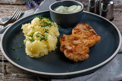 Pork chop served with mashed potatoes and cucumber salad.