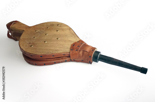 Natural wood and leather bellows for fireplaces and barbarcoas isolated on white background. Wooden fire bellows blower close up. Essential accessory for lighting fireplaces.