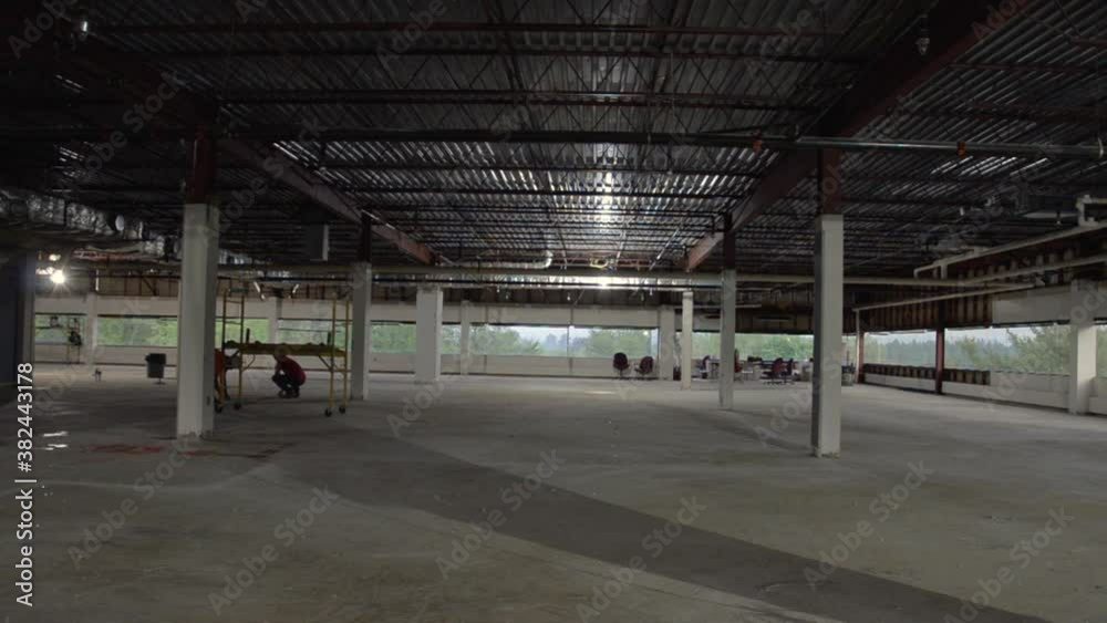 Wide interiors of an empty corporate building under construction, two men working Wide interiors of an empty corporate building under construction, two men working