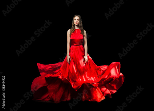 Pretty woman wearing red blowing evening gown on black background