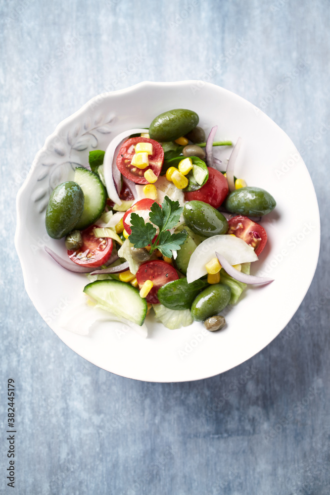 Healthy Salad with Green Olives, Baby Spinach, Cucumber, Cherry Tomatoes and Capers. Bright wooden background. Top view. Close up. Healthy Salad with Green Olives, Baby Spinach, Cucumber, Cherry Tomatoes and Capers. Bright wooden background. Top view. Close up.