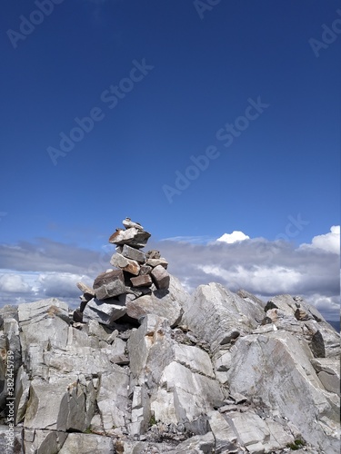 Décoration pyramidale d'un tas de pierre au sommet d'une montagne, dans l'immensité d'un ciel bleu au dessus de nuages lumineux, chemin de randonnée du Diamond Hill, montagne du Connemara en Irlande.