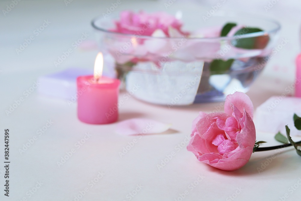 Fresh pink roses, water, petals, candles on a light background, body care products, natural home cosmetics, healthy lifestyle, alternative medicine Fresh pink roses, water, petals, candles on a light background, body care products, natural home cosmetics, healthy lifestyle, alternative medicine