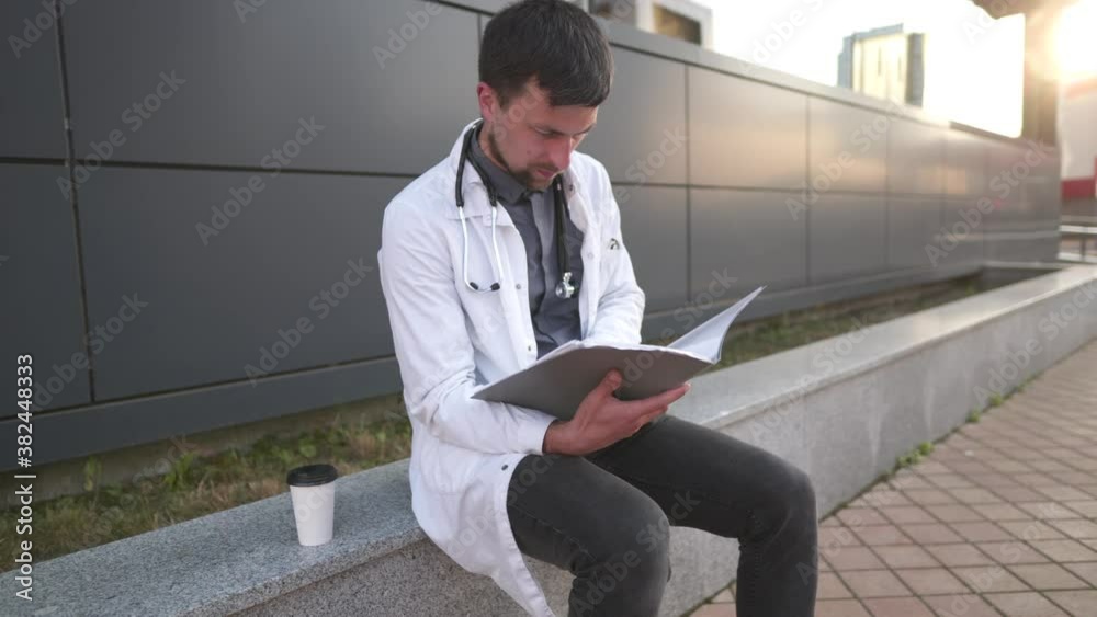 Tired overworked doctor reading medical report. Stressed doctor. Exhausted doctor resting after read medical records. Medicine concept. Tired medical physician in white coat hold folder with document