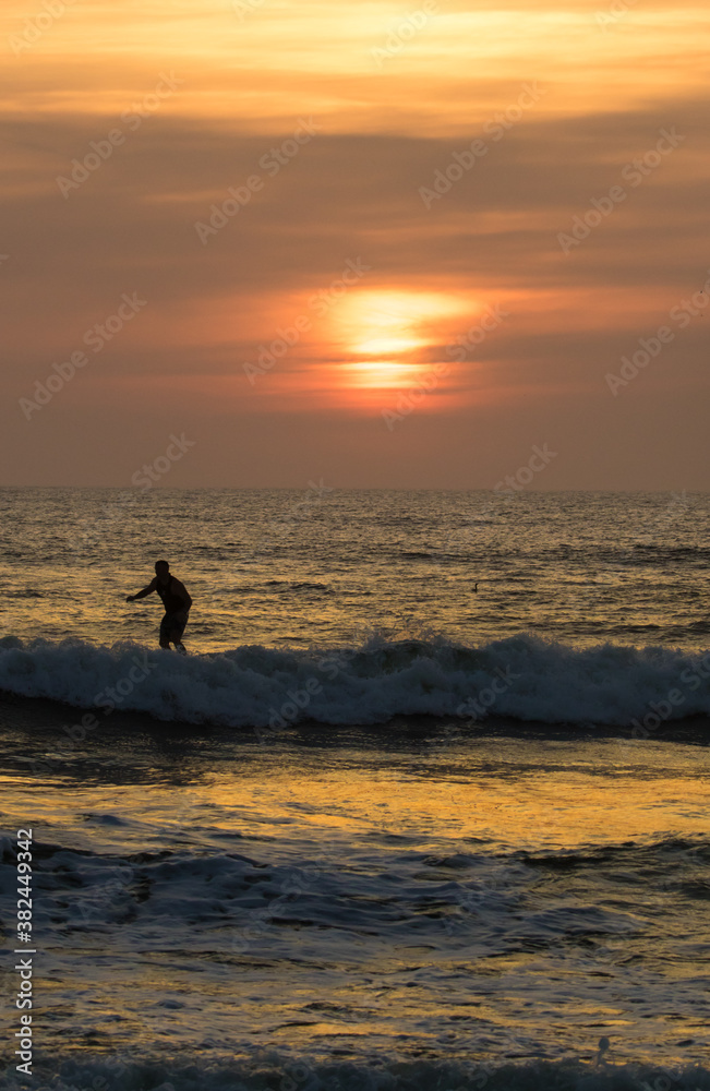 Sunrise over the atlantic ocean at St Augustine Beach in Florida.  A surfer is riding a wave in.
