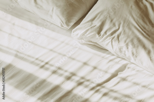 Comfortable bed with white linen at home. Detail with set of crisp white sheets and pillows. 