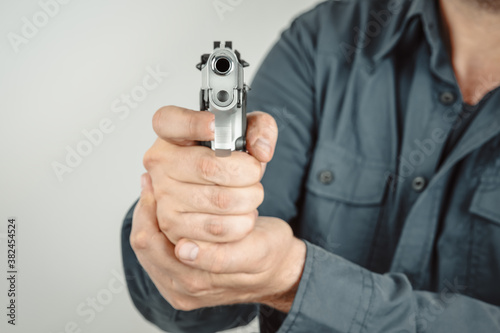 Man holding gun with two hands and taking aim at the camera. Crime, armed robbery concept.