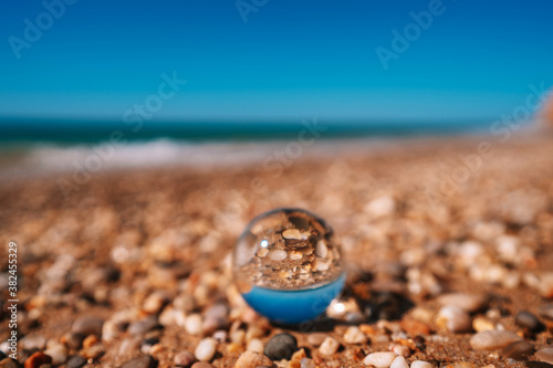 Beach with sea photographed through a crystal ball. The picture in the ball is in focus and the background is out of focus.