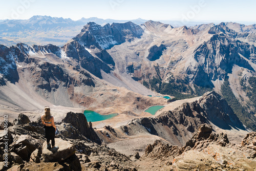 A woman standing at the summit of Mount Sneffles enjoying the view of the Blue Lakes.  photo