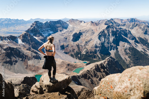 A woman standing at the summit of Mount Sneffles enjoying the view of the Blue Lakes.  photo