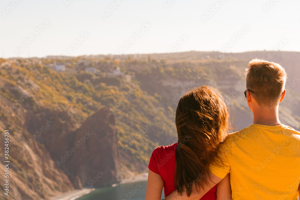 Happy young couple man and woman embrace on the edge of a cliff on the Cape, family youth travel concept