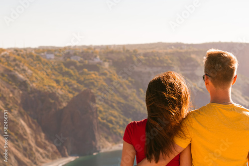 Happy young couple man and woman embrace on the edge of a cliff on the Cape, family youth travel concept