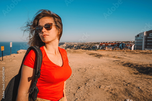 Portrait of a female tourist in sunglasses on a rocky landscape with sea in background