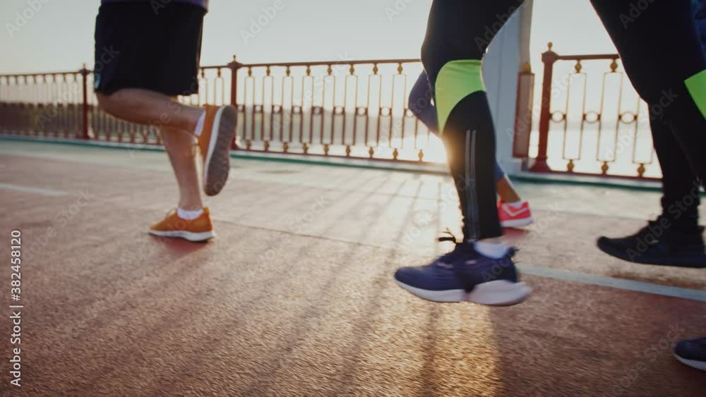 Group of people practicing morning jog workout on sports path in morning, close up of legs, slow motion