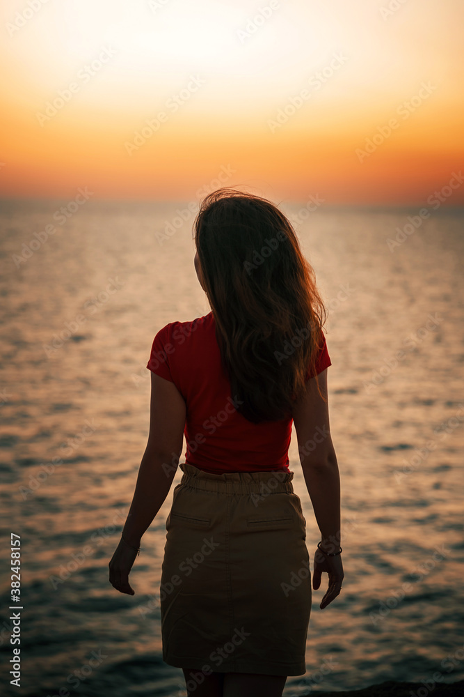 Silhouette of a slender young woman at sunset on the sea