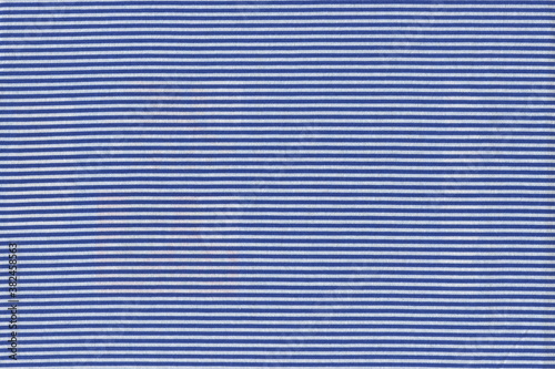 The texture of natural cotton fabric of knitwear in small stripes of blue and white. Abstract fabric background that resembles a pinstriped vest. Interesting comfortable fabric.