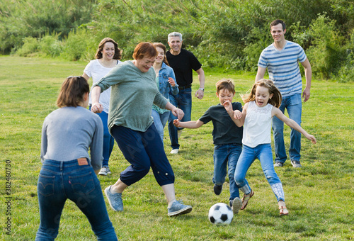 Smiling people of different ages playing football on grass