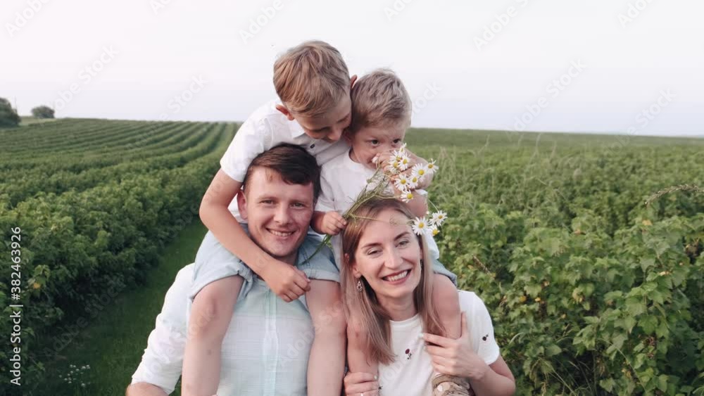 Family with kids are having fun outside. The little sons are playing and smiling. The parents are excited. Family with kids are having fun outside. The little sons are playing and smiling. The parents are excited.