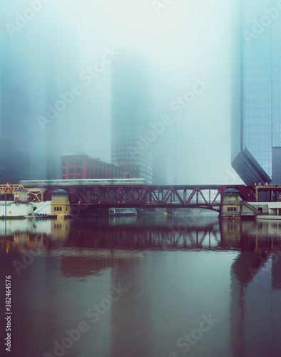 a foggy downtown city scene across a flooded river