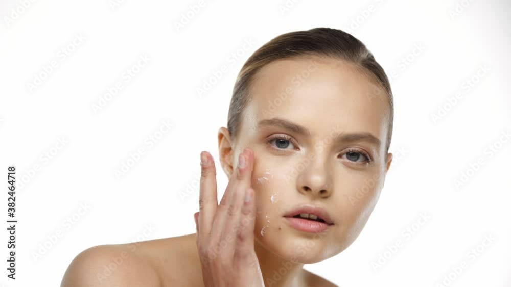 Portrait of young woman applying cream on face isolated on white Portrait of young woman applying cream on face isolated on white