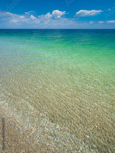 view from the beach to to emerald calm waters of sea under blue sky with copy space