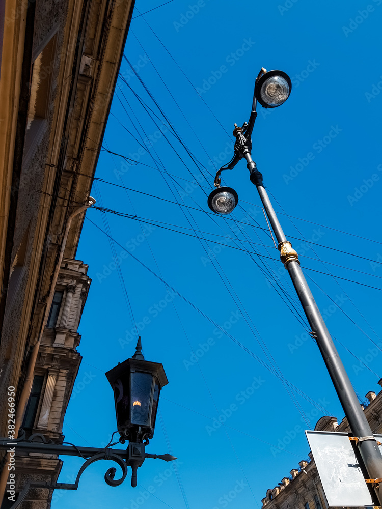 Old vintage black dark glass street lamp hanging on textured wall of beautiful building and lantern post, pillar in city of Saint Petersburg. Blue sky gradient. Contrast
