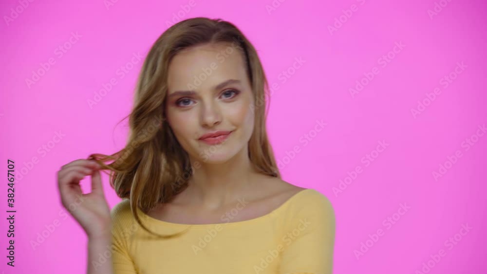 Dreamy young woman touching hair while posing isolated on pink Dreamy young woman touching hair while posing isolated on pink