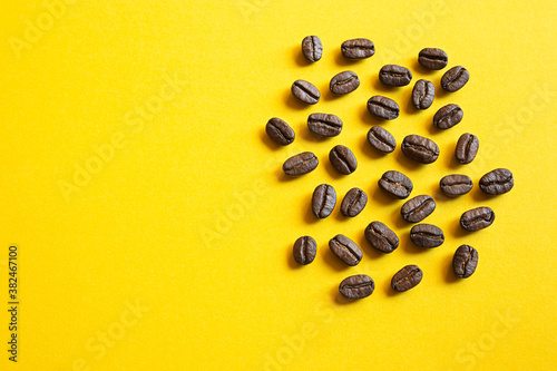 Coffee beans close-up on a bright yellow background with copy space